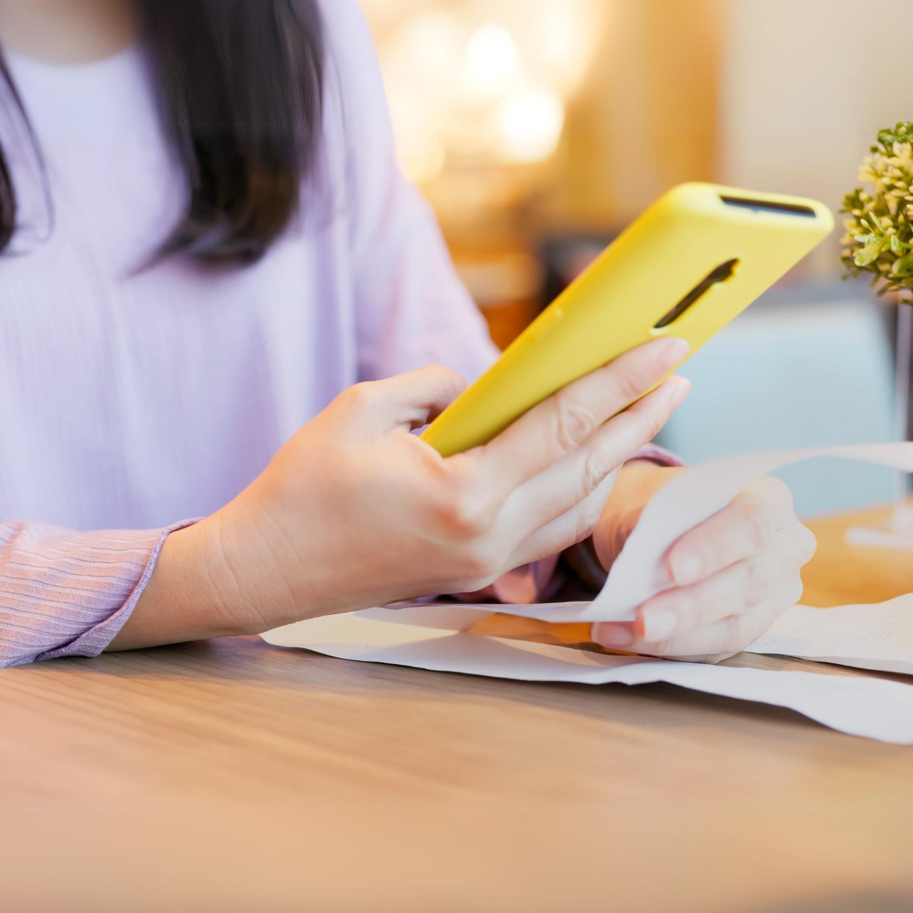 A female customer is holding her phone to check an email receipt while also holding a paper receipt