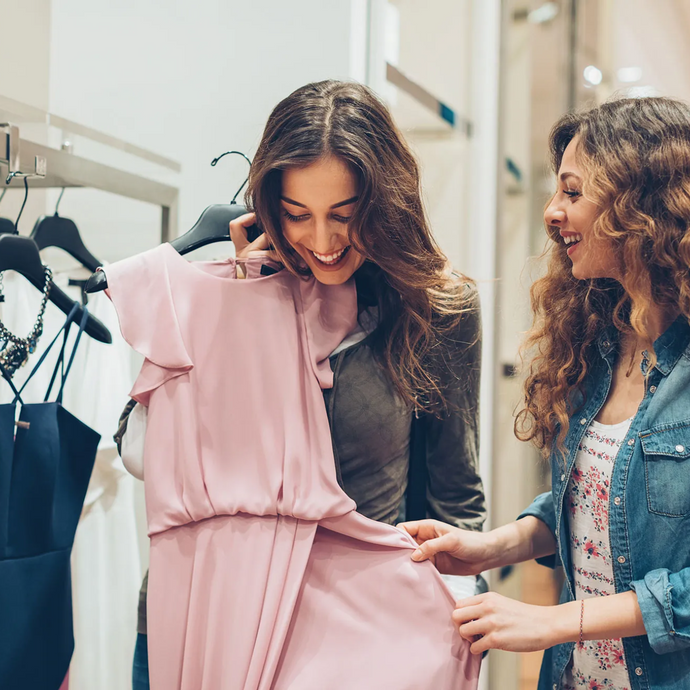 The clothing store employee is assisting a customer, who is very satisfied.