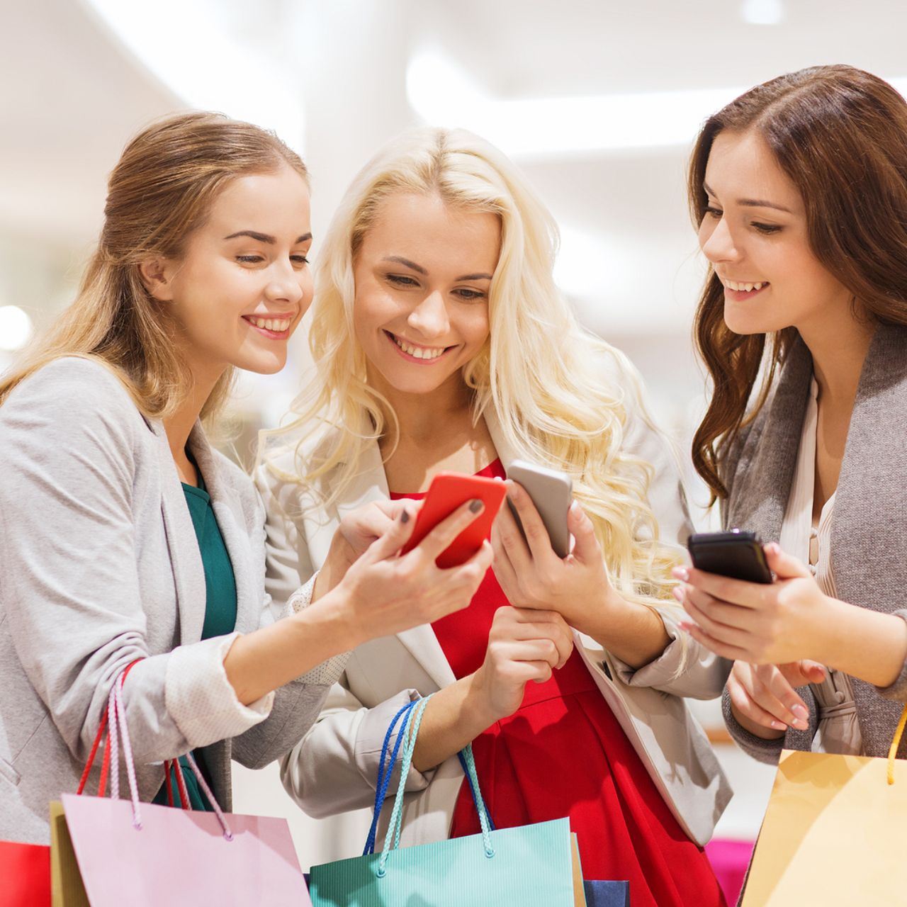 A group of friends holding many shopping bag and browsing their phones to find their desired items