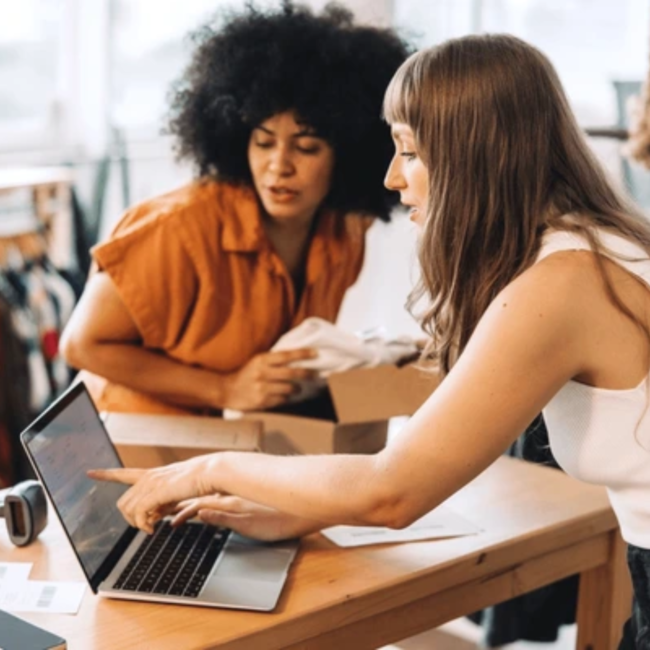 Two female clothing store owners are checking inventory on laptop