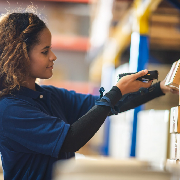 An employee is using an mPOS device to verify the goods in the warehouse